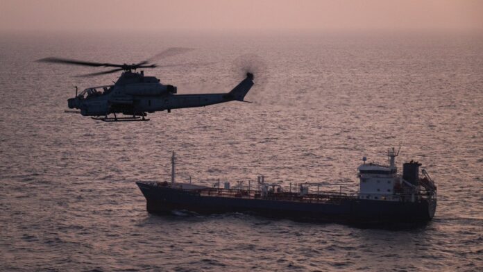 File Image: A U.S. Marine Corps AH-1Z Viper attack helicopter patrols near a commercial vessel