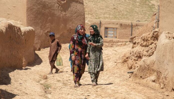 Two girls walk through a village in Baghlan province, Afghanistan.