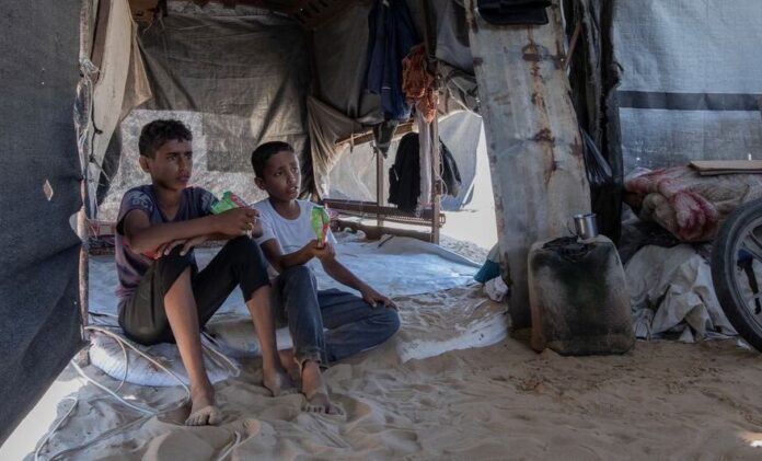 Two young brothers sitting outside their family’s tent in Gaza.